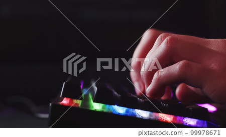 Male hands is typing on the computer keyboard, close up view. Man working on the pc computer. Human hands typing on the colourful gaming keyboard. Fingers typing on the led rgb keyboard. 99978671