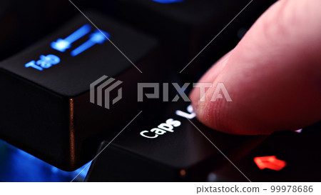 Human finger clicks on the Caps Lock key on the computer keyboard, close up view. Man finger presses Caps Lock on the keyboard key, macro shot. Rgb led light keyboard Human finger clicks on the Caps Lock key on the computer keyboard, close up view. Man finger presses Caps Lock on the keyboard key, macro shot. Rgb led light keyboard 99978686