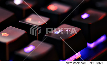 Keyboard key  - Windows - macro shot.  Modern gaming keyboard close-up with beautiful color backlight.  Macro shooting of the rgb computer keyboard with backlight.  Low angle view with soft focus. 99978690
