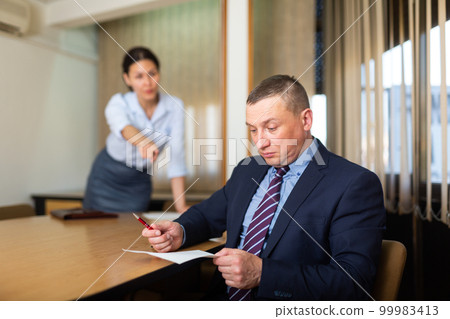 Shocked office employe reading papers with dissatisfied female manager Shocked office employe reading papers with dissatisfied female manager 99983413
