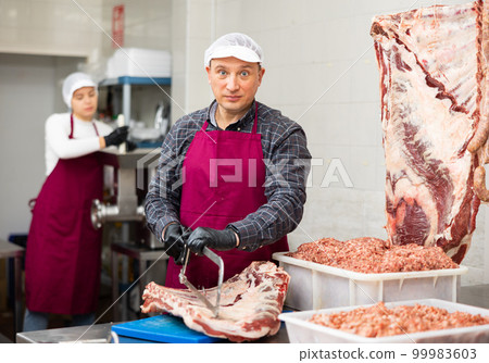 Adult male butcher sawing beef ribs 99983603