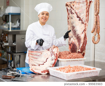 Young woman butcher holding beef ribs 99983983