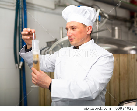 Brewery owner checking alcoholic content in beer with hydrometer 99984025