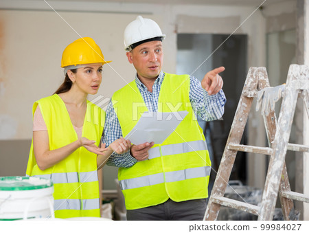 Man and woman builders talking in house 99984027