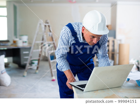 Man builder using laptop in construction site 99984151