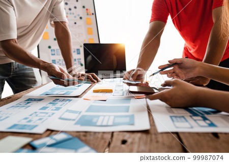 Close up ux developer and ui designer brainstorming about mobile app interface wireframe design at modern office. Creative digital development agency 99987074