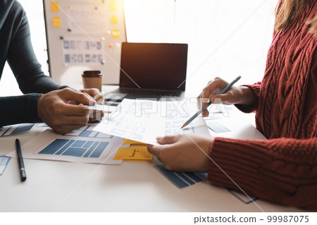 Close up ux developer and ui designer brainstorming about mobile app interface wireframe design at modern office. Creative digital development agency 99987075