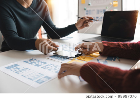 Close up ux developer and ui designer brainstorming about mobile app interface wireframe design at modern office. Creative digital development agency 99987076