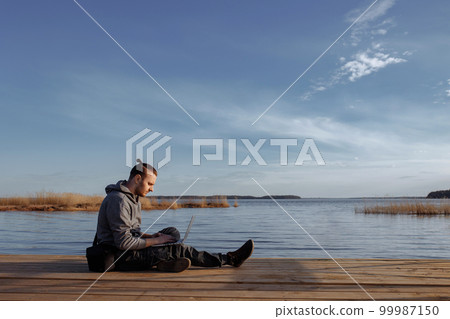 Young man working online on laptop outside 99987150