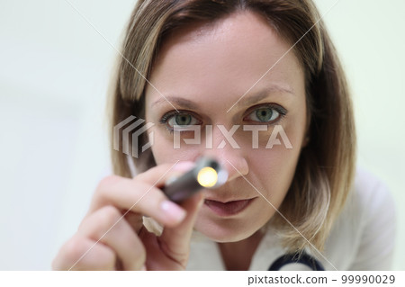 Close up of female doctor with medical instrument in hand looking at camera. 99990029
