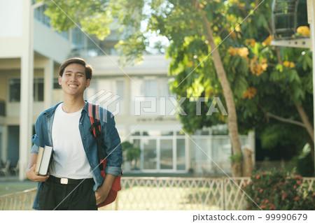 Student standing outdoor and holding books. 99990679