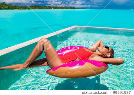 Summer swimming pool woman relaxing on donut float enjoying luxury resort vacation sunbathing fun. Red swimsuit suntan girl happy Summer swimming pool woman relaxing on donut float enjoying luxury resort vacation sunbathing fun. Red swimsuit suntan girl happy 99991927