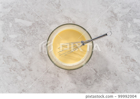 Flat lay. Mixing ingredients in a glass mixing bowl to bake funfettti bundt cake. 99992004
