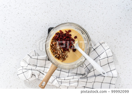 Flat lay. Melting white chocolate chips and other ingredients in a glass mixing bowl over boiling water to prepare white chocolate cranberry pecan fudge. Flat lay. Melting white chocolate chips and other ingredients in a glass mixing bowl over boiling water to prepare white chocolate cranberry pecan fudge. 99992099
