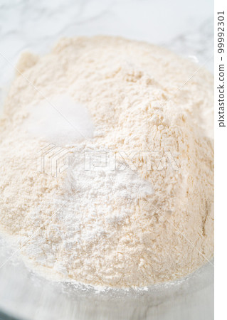 Lemon wedge cookies with lemon glaze. Mixing dry ingredients with a hand whisk in a large glass mixing bowl to bake lemon wedge cookies. Lemon wedge cookies with lemon glaze. Mixing dry ingredients with a hand whisk in a large glass mixing bowl to bake lemon wedge cookies. 99992301