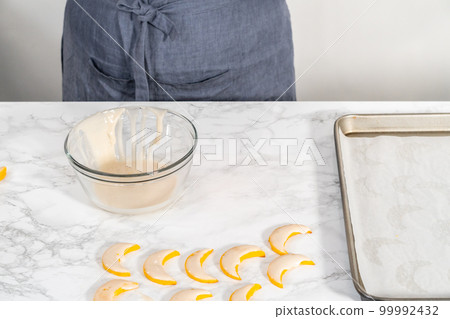 Lemon wedge cookies with lemon glaze. Dipping lemon cookies into a lemon glaze. 99992432