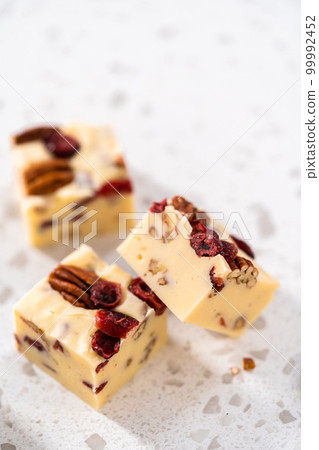Close up view. Homemade white chocolate cranberry pecan fudge pieces on the kitchen counter. 99992452
