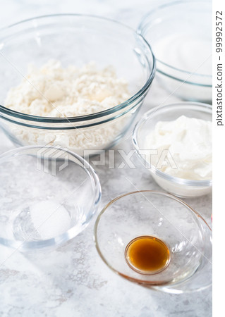 Ingredients in glass mixing bowls to bake funfettti bundt cake. 99992572
