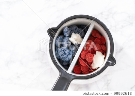 Melting chocolate chips in a candy melting pot to make red, white, and blue chocolate-covered pretzel twists. Melting chocolate chips in a candy melting pot to make red, white, and blue chocolate-covered pretzel twists. 99992618