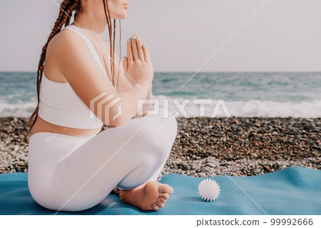 Close up Yoga Hand Gesture of Woman Doing an Outdoor meditation. Blurred sea background. Woman on yoga mat in beach meditation, mental health training or mind wellness by ocean, sea. Selective focus Close up Yoga Hand Gesture of Woman Doing an Outdoor meditation. Blurred sea background. Woman on yoga mat in beach meditation, mental health training or mind wellness by ocean, sea. Selective focus 99992666