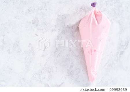 Pink vanilla buttercream frosting in a piping bag. Pink vanilla buttercream frosting in a piping bag. 99992689