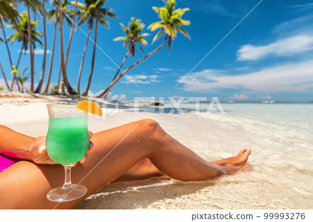Tropical frozen blue drink Hawaiian cocktail woman drinking glass on beach vacation travel in Caribbean destination. Summer fun lifestyle 99993276