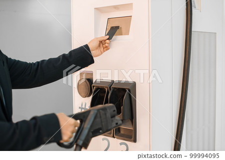 Asian entrepreneur paying with card at charging station Asian entrepreneur paying with card at charging station 99994095