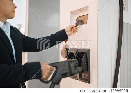 Asian entrepreneur paying with card at charging station 99994096