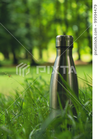 Water bottle. Reusable steel thermo water bottle on green grass. Sustainable lifestyle. Plastic free zero waste free living. Go green Environment protection 99994479