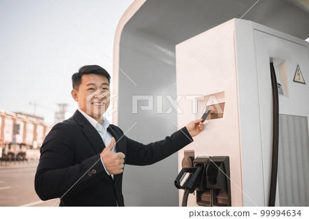 Businessman paying with card for charging electro car 99994634
