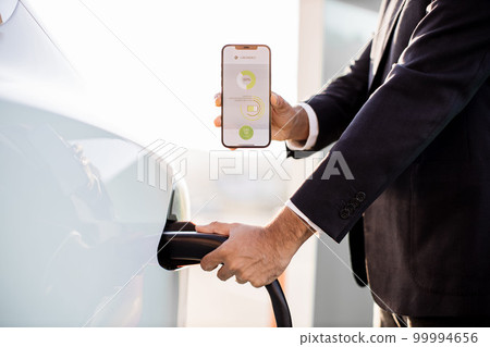 Man showing mobile app with charging status of electric car Man showing mobile app with charging status of electric car 99994656