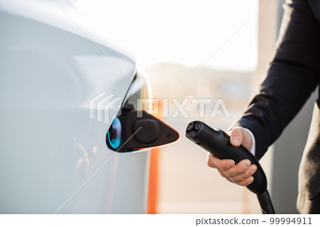 Crop of male hand inserting charging cable into car Crop of male hand inserting charging cable into car 99994911