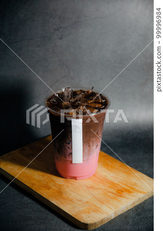 Close up of cocoa strawberry in plastic glass with white sticker tag on wooden plate with gray background Close up of cocoa strawberry in plastic glass with white sticker tag on wooden plate with gray background 99996984