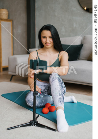 A fitness woman teacher communicates with her students via video broadcast and does exercises with them A fitness woman teacher communicates with her students via video broadcast and does exercises with them 99997149