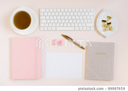 Office desk, notebooks, keyboard and colored pencils, a cup of tea, mimosa flowers on a beige background. Minimal business concept for women. 99997659
