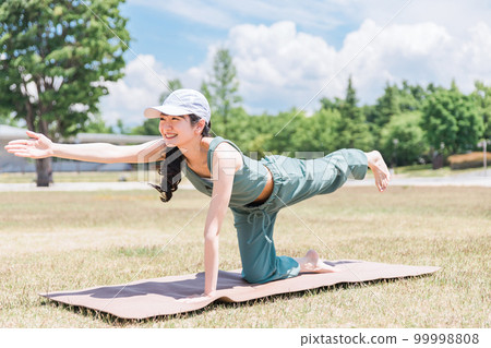 A woman doing yoga, stretching, and exercising using a yoga mat in the park (tiger pose) A woman doing yoga, stretching, and exercising using a yoga mat in the park (tiger pose) 99998808