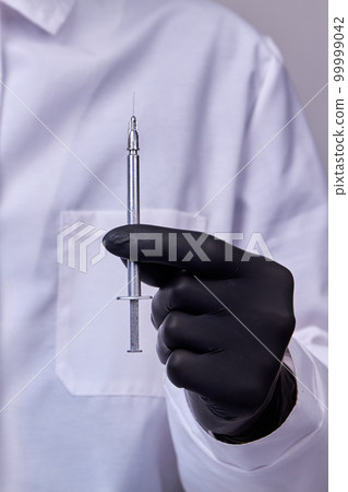 Surgeon hand in black glove holding cosmetic syringe. Clenching with thumb and point finger. Surgeon hand in black glove holding cosmetic syringe. Clenching with thumb and point finger. 99999042