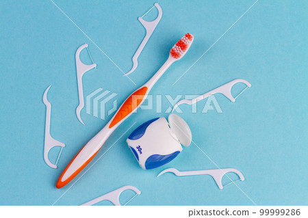Toothbrush with dental floss picks and thread. Top view blue background. Toothbrush with dental floss picks and thread. Top view blue background. 99999286
