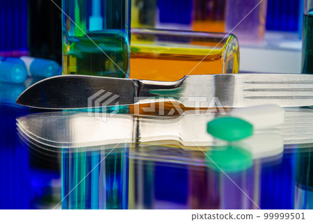 Metallic surgical knife and bottles of medicine. Science research concept. 99999501