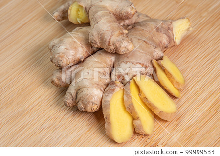 Fresh whole ginger root on wooden background close up. Spices and herbs seasoning for cooking. Medicinal herbs. Use of slice ginger in aromatherapy. High content of essential oils in the plant Fresh whole ginger root on wooden background close up. Spices and herbs seasoning for cooking. Medicinal herbs. Use of slice ginger in aromatherapy. High content of essential oils in the plant 99999533