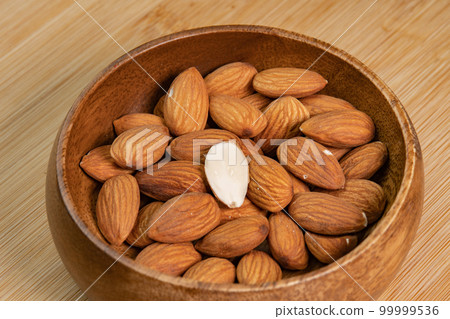 Almond nuts in wooden bowl on wooden background close up. Product rich in minerals and vitamins. Almond kernels. Healthy skin and hair and natural healing oil treatment Almond nuts in wooden bowl on wooden background close up. Product rich in minerals and vitamins. Almond kernels. Healthy skin and hair and natural healing oil treatment 99999536
