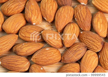 Almond nuts on wooden background close up. Product rich in minerals and vitamins. Almond kernels. Healthy skin and hair and natural healing oil treatment Almond nuts on wooden background close up. Product rich in minerals and vitamins. Almond kernels. Healthy skin and hair and natural healing oil treatment 99999543