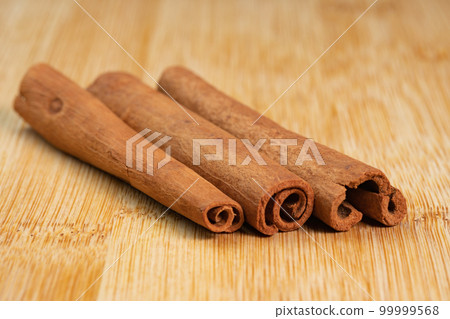 Cinnamon sticks on a wooden background. Fragrant cinnamon seasoning close-up. Spices with cinnamon. Food cooking video concept. ingredients for warm wine, mulled wine Cinnamon sticks on a wooden background. Fragrant cinnamon seasoning close-up. Spices with cinnamon. Food cooking video concept. ingredients for warm wine, mulled wine 99999568