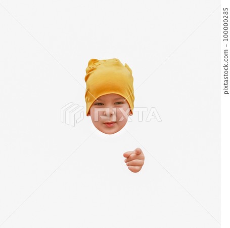 The head of a little boy in a yellow hat and a finger pointing at you isolated on a white background The head of a little boy in a yellow hat and a finger pointing at you isolated on a white background 100000285