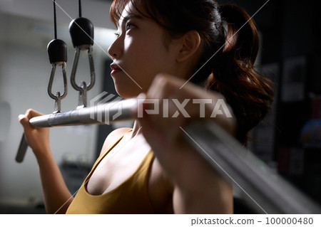 Young woman doing muscle training using a training machine Young woman doing muscle training using a training machine 100000480