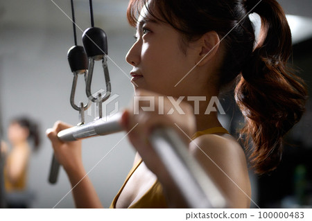 Young woman doing muscle training using a training machine Young woman doing muscle training using a training machine 100000483