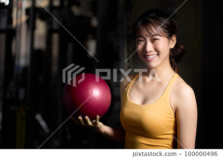 A young woman looking while holding a stretch ball 100000496