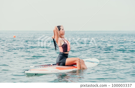 Sea woman sup. Silhouette of happy young woman in pink bikini, surfing on SUP board, confident paddling through water surface. Idyllic sunset. Active lifestyle at sea or river 100003337
