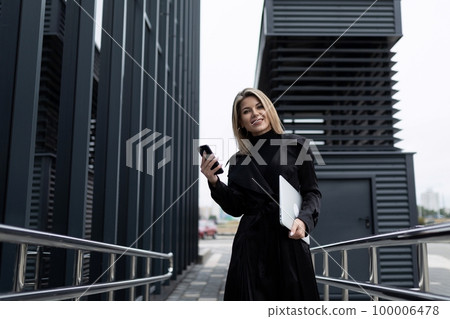 a business woman holds a phone in her hand and speaks with a partner on a cellular connection 100006478
