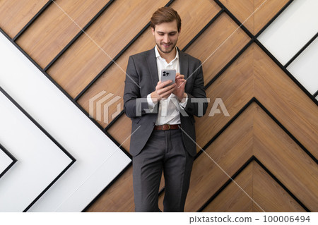 businessman broker typing a message in a smartphone while in the office businessman broker typing a message in a smartphone while in the office 100006494